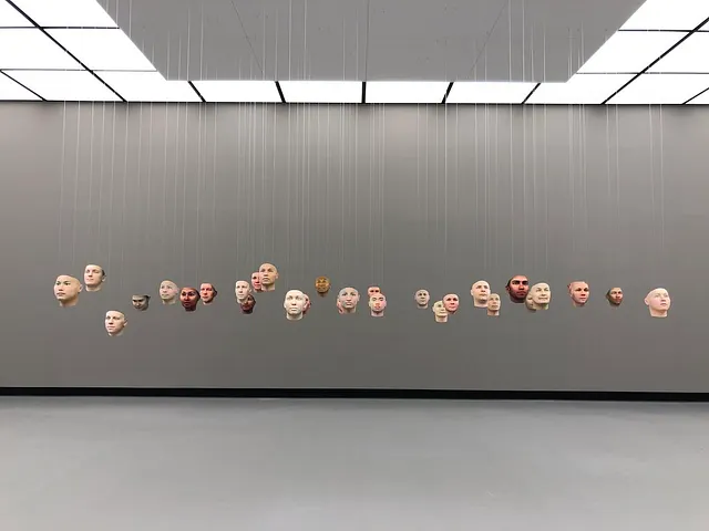 A room with human face masks suspended by lines.